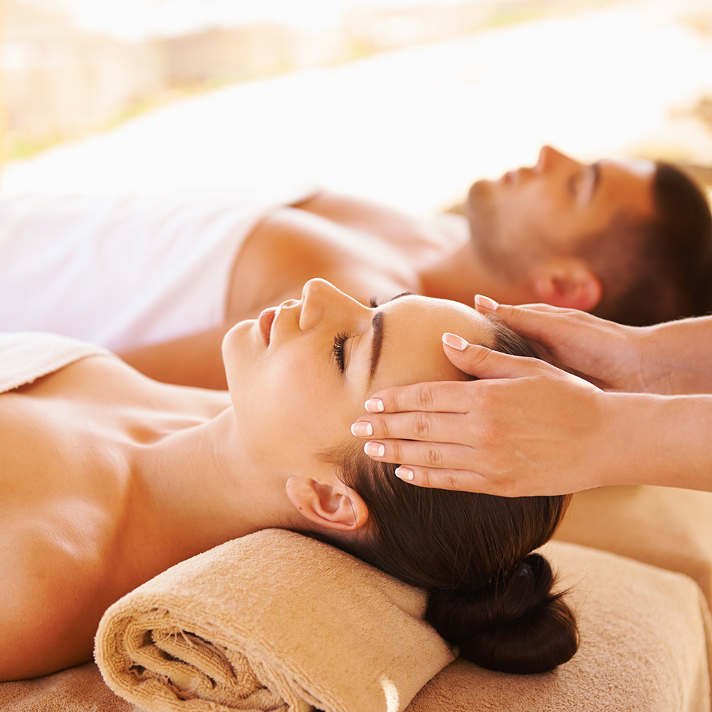 Para podczas masażu olejkami w przytulnym hotelowym spa z ziołowymi świecami