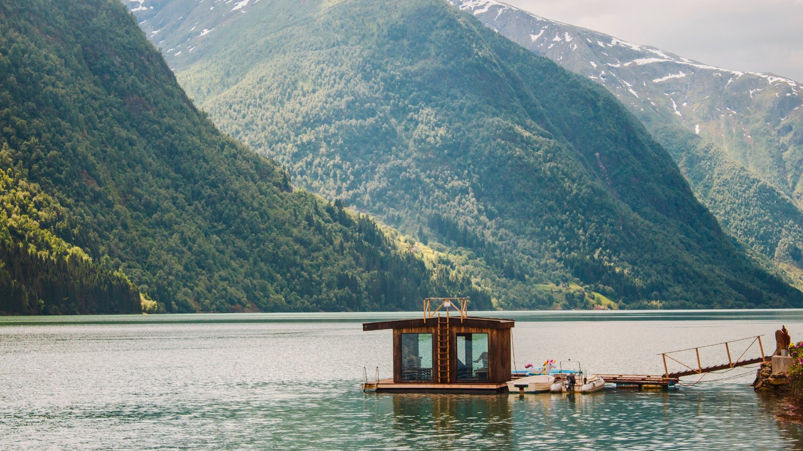 kobieta medytująca na zielonym klifie z panoramicznym widokiem na norweskie fiordy i morze