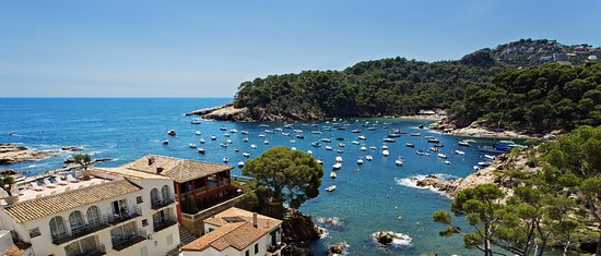 rodzina spacerująca po piaszczystej plaży z widokiem na Costa Brava