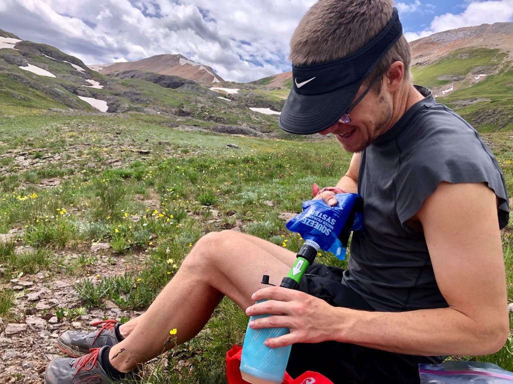 użytkownik płuczący membranę filtra pod bieżącą wodą w górskim potoku