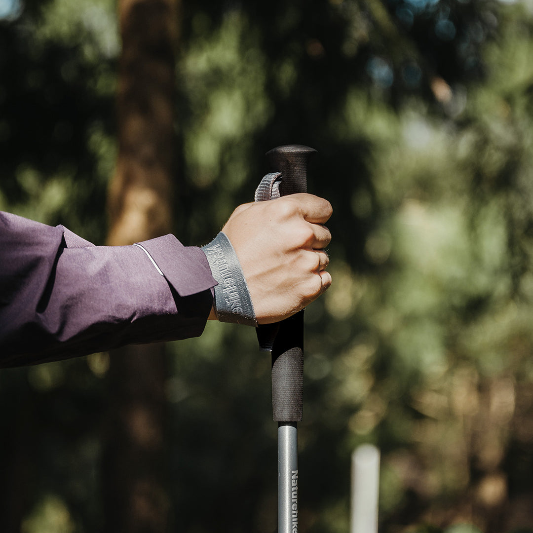 kobieta pakująca składane kijki do bocznej kieszeni plecaka turystycznego