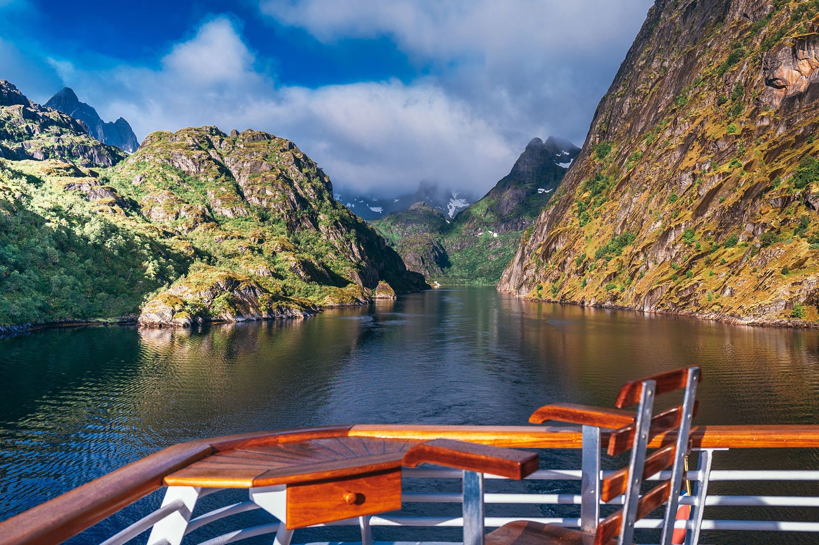 mężczyzna unoszący się na materacu w jacuzzi z widokiem na norweskie góry i fiord